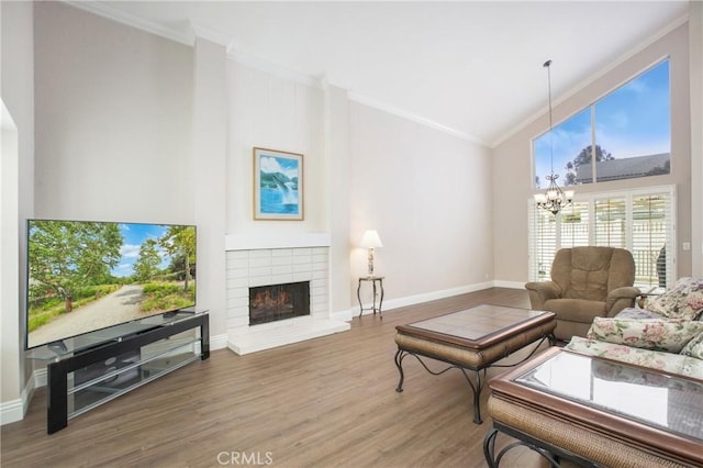 living room featuring hardwood / wood-style flooring, ornamental molding, an inviting chandelier, and a fireplace