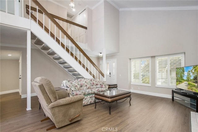 living room with crown molding, a towering ceiling, and hardwood / wood-style floors