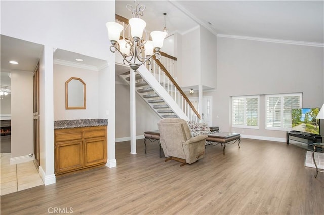 living room with crown molding, a towering ceiling, and light wood-type flooring