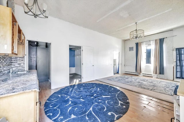 entryway featuring an inviting chandelier, a baseboard radiator, sink, and light wood-type flooring