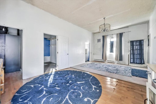 entrance foyer featuring a baseboard heating unit, a textured ceiling, hardwood / wood-style floors, and a chandelier