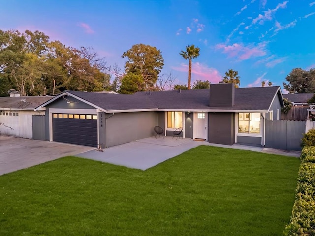 single story home featuring a garage and a lawn