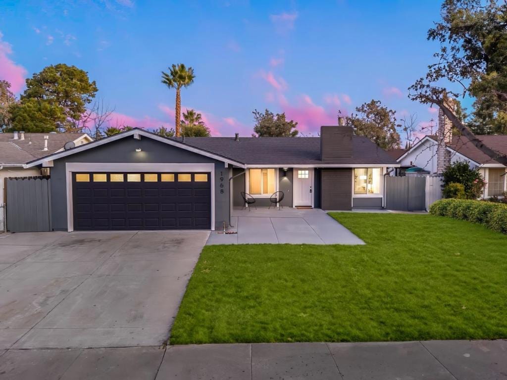 ranch-style home featuring a garage and a lawn