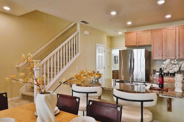 kitchen featuring stone counters, a breakfast bar area, and stainless steel refrigerator