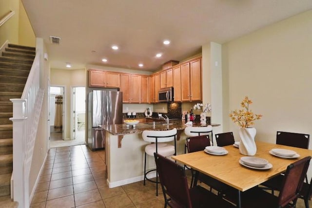 kitchen featuring sink, a breakfast bar area, light tile patterned floors, appliances with stainless steel finishes, and kitchen peninsula