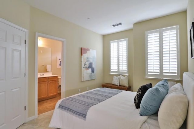 bedroom featuring ensuite bathroom and multiple windows