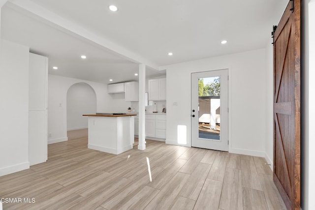 interior space featuring white cabinetry, a barn door, a center island, and light hardwood / wood-style flooring