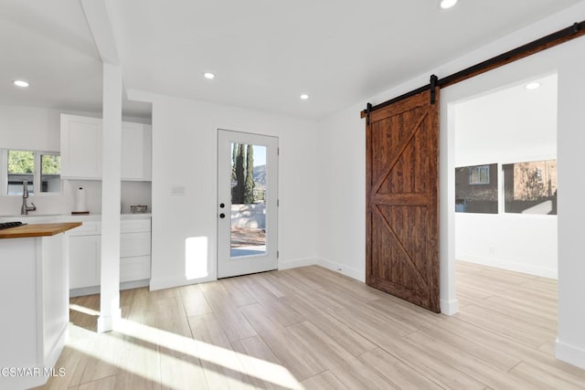 interior space featuring sink, a wealth of natural light, a barn door, and light wood-type flooring