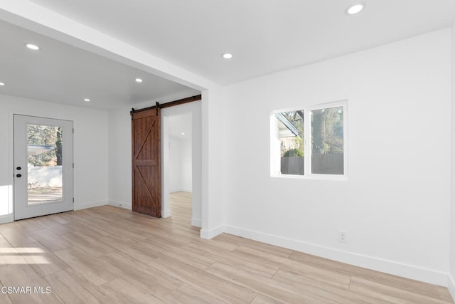 spare room featuring plenty of natural light, a barn door, and light hardwood / wood-style flooring