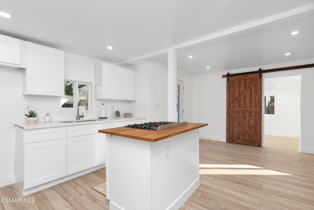 kitchen with butcher block counters, white cabinetry, a barn door, and stainless steel gas stovetop