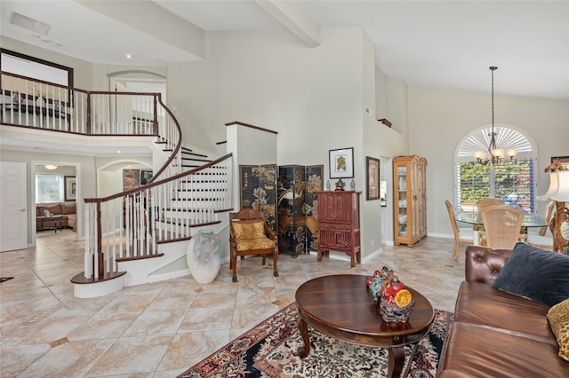 living room featuring beam ceiling, a chandelier, and a high ceiling