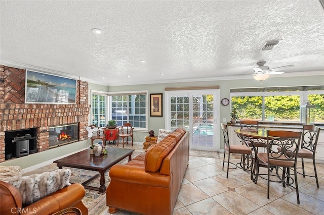 tiled living room featuring a brick fireplace, a textured ceiling, ornamental molding, and ceiling fan