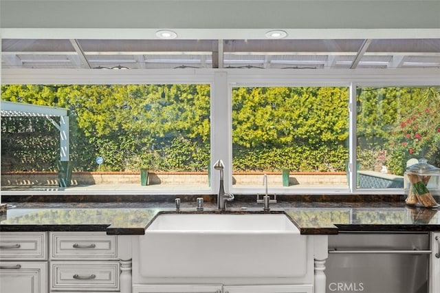 kitchen with dark stone countertops, sink, and white cabinets