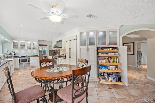dining space featuring visible vents, a ceiling fan, washer and dryer, recessed lighting, and arched walkways