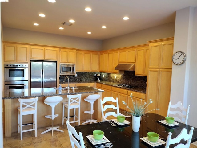 kitchen with stainless steel appliances, sink, dark stone counters, and backsplash