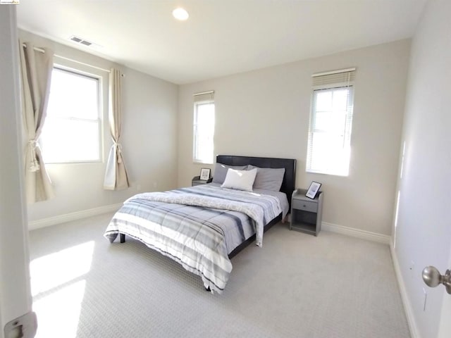 bedroom featuring light colored carpet and multiple windows