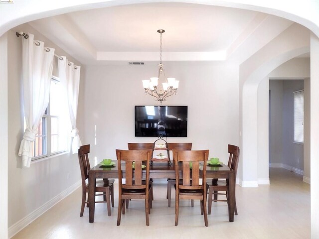 dining space featuring a notable chandelier and a tray ceiling