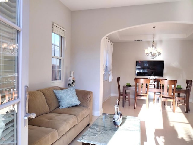 living room with a raised ceiling and an inviting chandelier