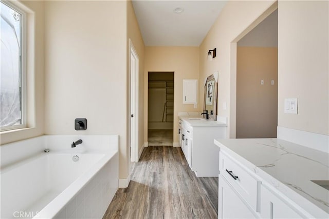 bathroom featuring vanity, hardwood / wood-style floors, and a relaxing tiled tub