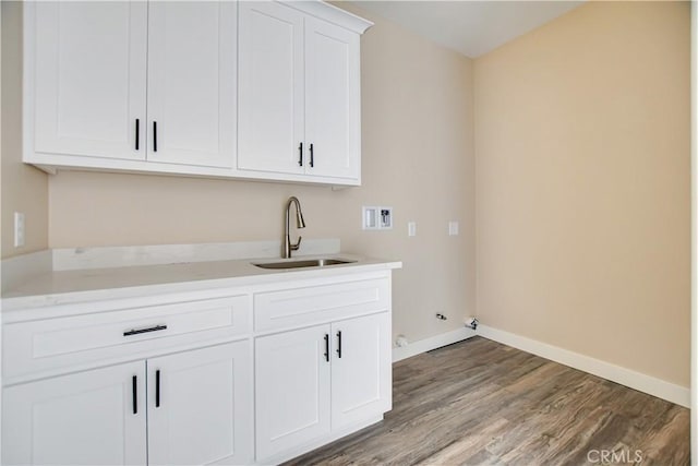 washroom featuring gas dryer hookup, sink, hardwood / wood-style floors, cabinets, and washer hookup