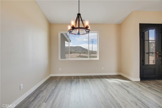 unfurnished dining area featuring hardwood / wood-style flooring and an inviting chandelier