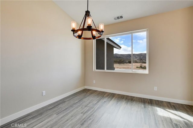 unfurnished dining area featuring wood-type flooring, a mountain view, vaulted ceiling, and a notable chandelier