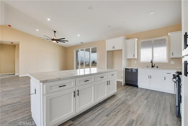 kitchen featuring stainless steel gas stove, a center island, black dishwasher, light stone countertops, and white cabinets