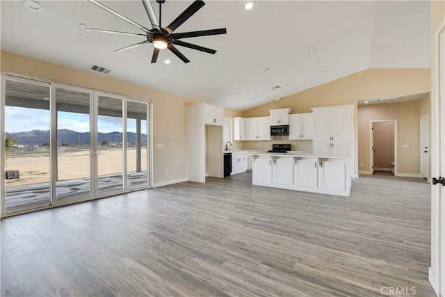 kitchen featuring ceiling fan, white cabinetry, a kitchen island, a mountain view, and light wood-type flooring