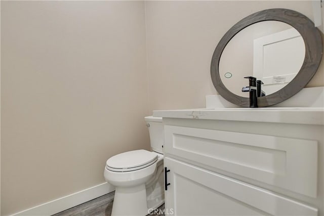 bathroom featuring wood-type flooring, toilet, and vanity