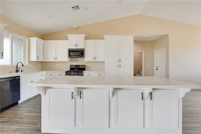 kitchen featuring light stone counters, stainless steel appliances, a breakfast bar, and a kitchen island