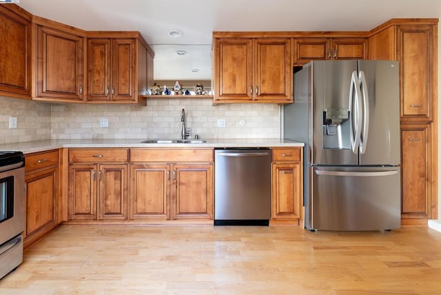 kitchen with sink, appliances with stainless steel finishes, tasteful backsplash, light stone counters, and light hardwood / wood-style floors