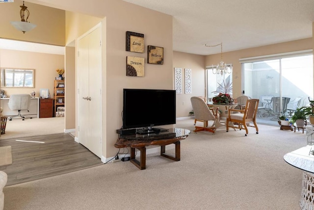 carpeted living room featuring an inviting chandelier