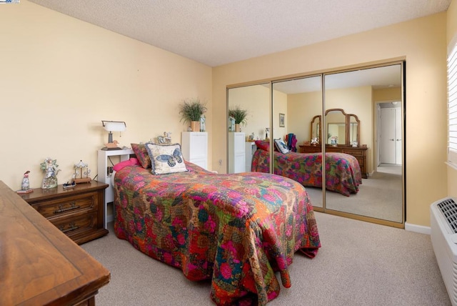 bedroom with light carpet, a textured ceiling, and a closet