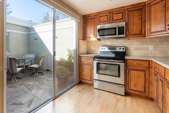 kitchen featuring decorative backsplash, light wood-type flooring, and appliances with stainless steel finishes