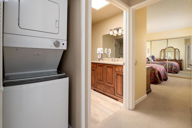 washroom with sink, stacked washer / drying machine, and light colored carpet