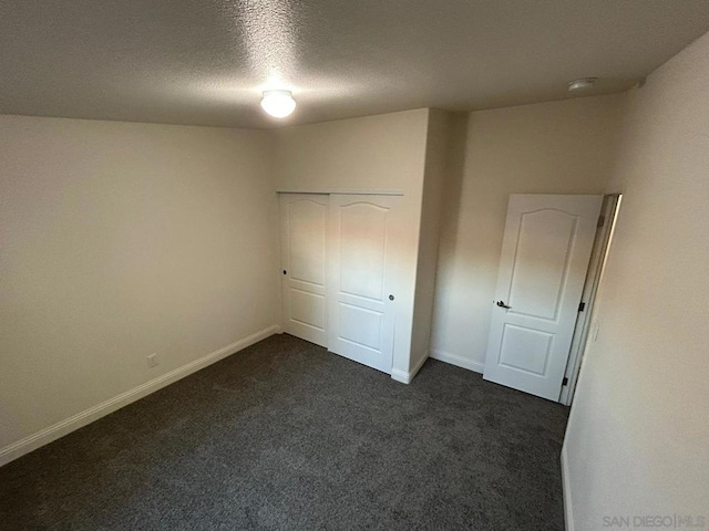 unfurnished bedroom featuring a closet, a textured ceiling, and dark colored carpet