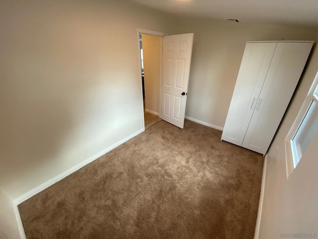 unfurnished bedroom with light carpet and a closet