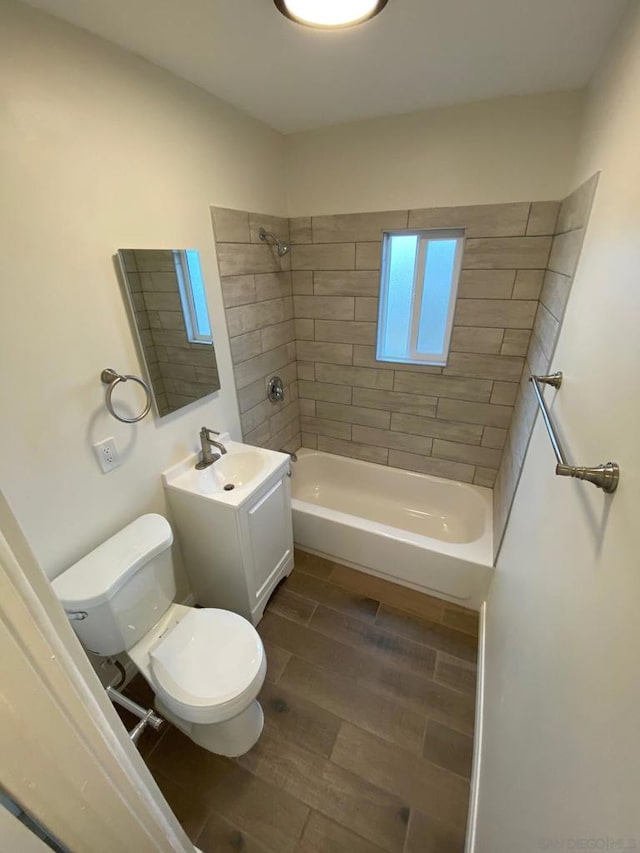 full bathroom featuring tiled shower / bath, vanity, and toilet