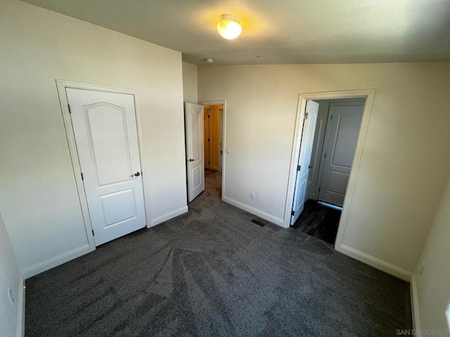 unfurnished bedroom featuring lofted ceiling and dark carpet