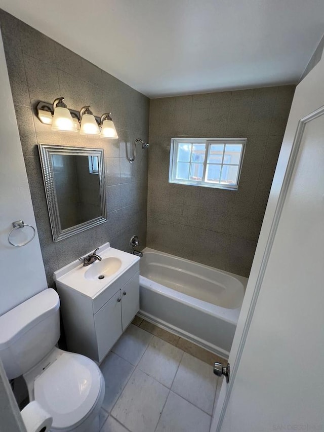 full bathroom featuring tile patterned flooring, tile walls, vanity, tiled shower / bath, and toilet