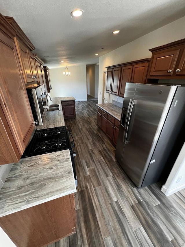 kitchen featuring stainless steel appliances, dark hardwood / wood-style floors, a notable chandelier, and a textured ceiling