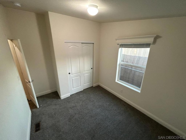 unfurnished bedroom featuring dark carpet and a closet