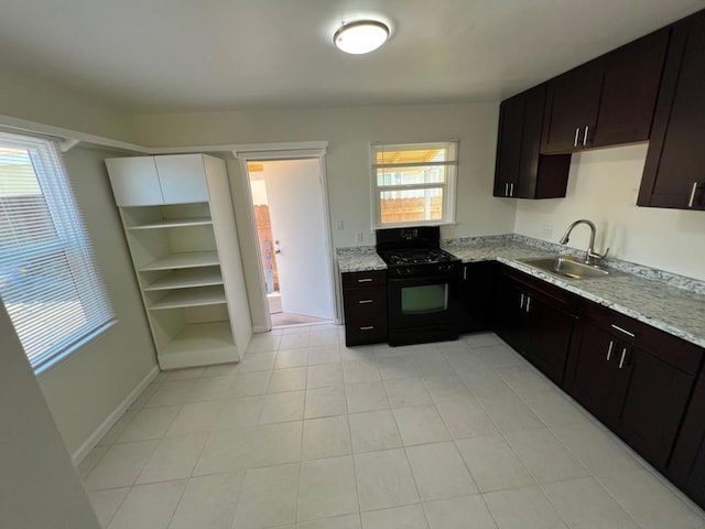 kitchen with light stone counters, dark brown cabinetry, sink, and black gas range