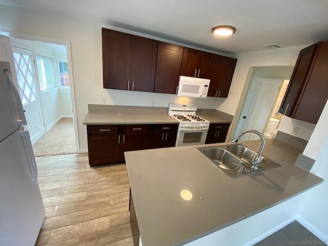 kitchen with white appliances, kitchen peninsula, sink, and dark brown cabinets