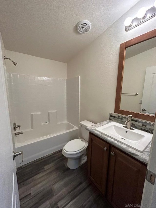 full bathroom featuring tub / shower combination, vanity, wood-type flooring, a textured ceiling, and toilet