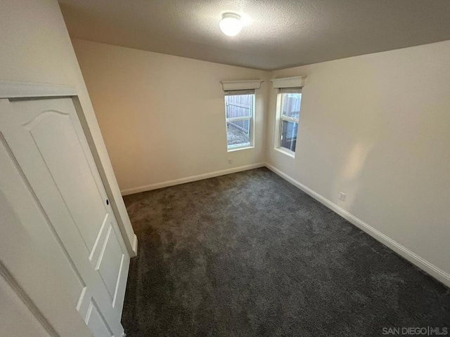 carpeted empty room featuring a textured ceiling