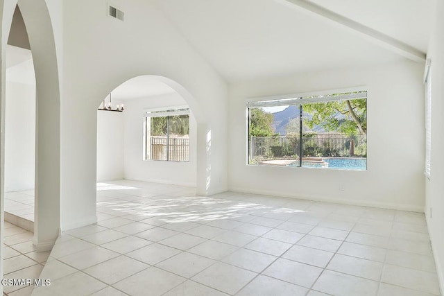 tiled spare room featuring high vaulted ceiling and an inviting chandelier