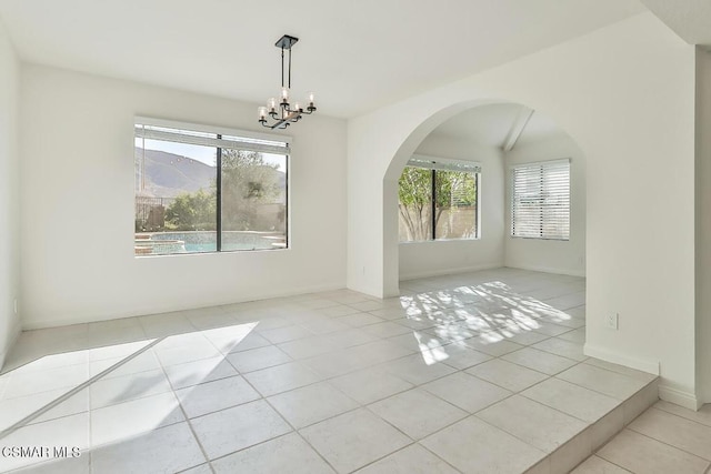 unfurnished room featuring a notable chandelier, a mountain view, and light tile patterned flooring