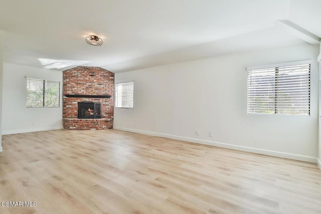 unfurnished living room with lofted ceiling, a fireplace, and light hardwood / wood-style flooring