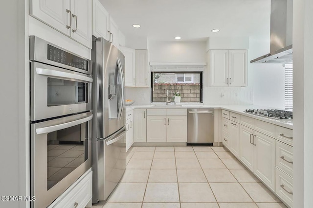 kitchen featuring stainless steel appliances, island exhaust hood, a healthy amount of sunlight, and white cabinetry